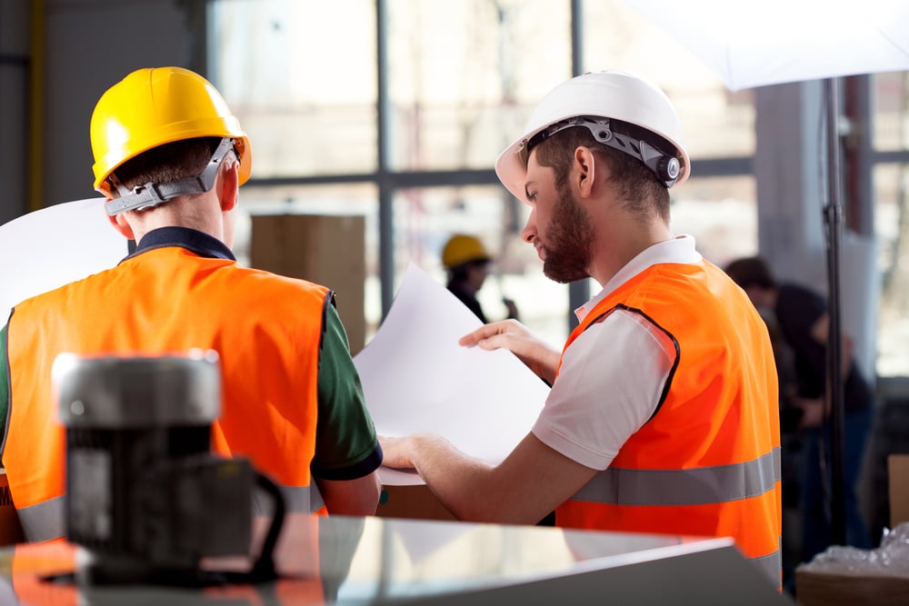 Male factory worker and supervisor are analyzing plans Male factory worker and supervisor are analyzing plans